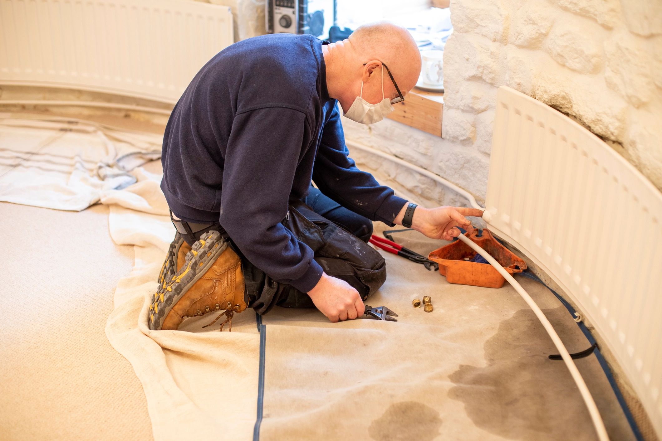 Plumber adjusting a radiator pipe during a home repair
