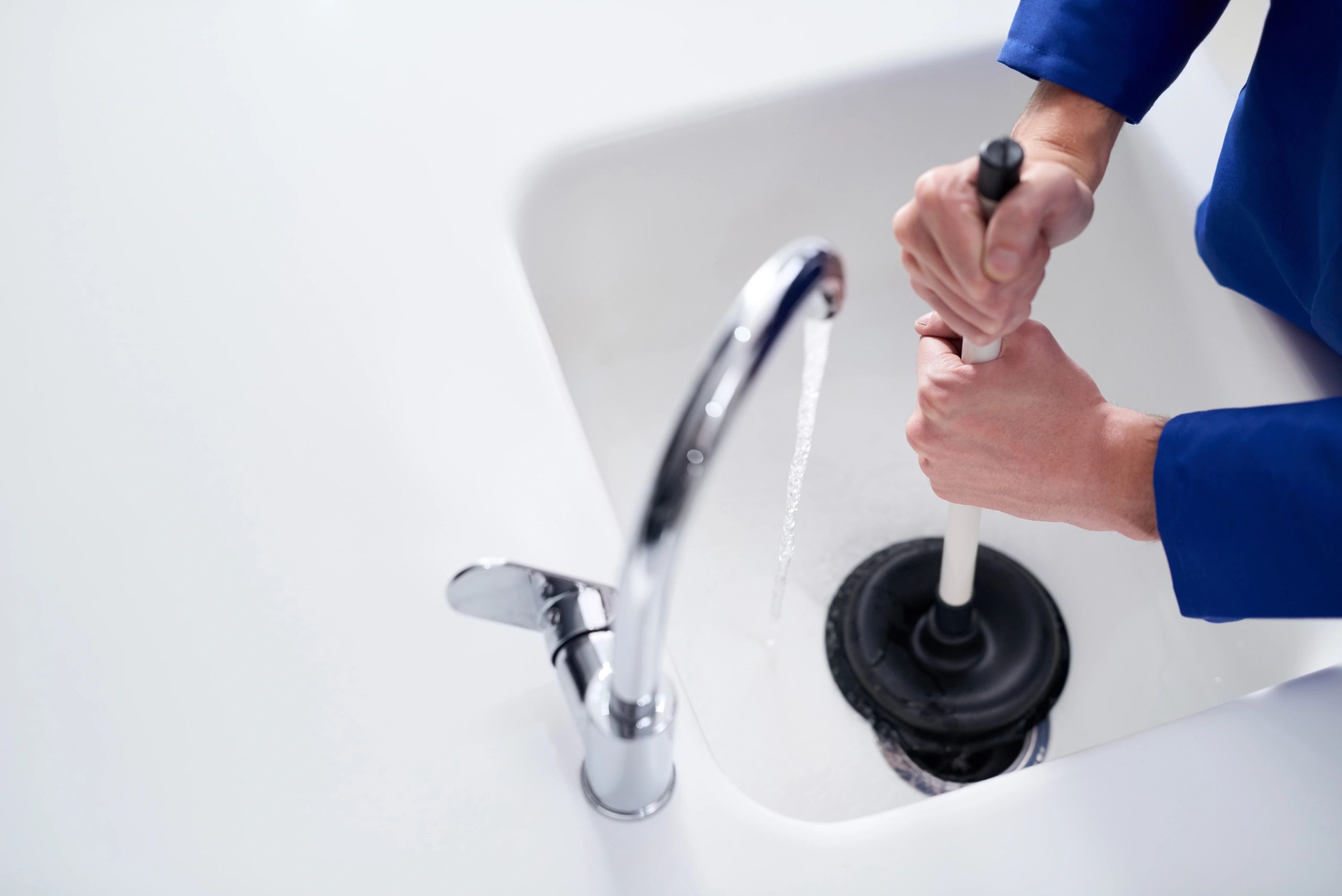 Plumber unblocking a drain with a plunger